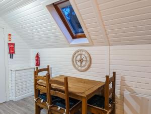 a dining room with a table and a clock on the wall at Boann 5 - Hot Tub-Hunting Tower Lodges-Luxury-Families-Romantic in Perth