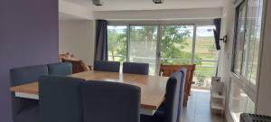 mesa de comedor con sillas azules y ventana grande en Alfonsina Holiday Home en Sierra de la Ventana