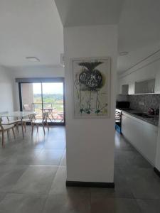 a white kitchen with a table and a picture on the wall at Excelente departamento en pleno centro in Puerto Iguazú
