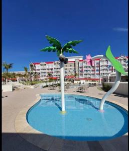 a palm tree in a pool in front of a hotel at Apt no Thermas São Pedro Resort in São Pedro