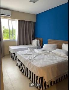 two beds in a bedroom with a blue wall at Apt no Thermas São Pedro Resort in São Pedro