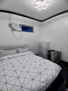 EJ'S House/ Room في Dulag: غرفة نوم بسرير ابيض ومروحة