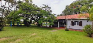 a house with a green yard next to a building at Chácara Monteiro - Próximo ao Thermas Water Park in São Pedro