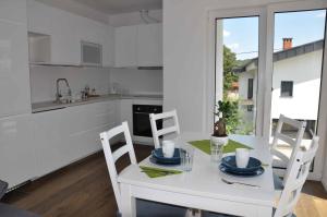 a white kitchen with a white table and chairs at Apartments Trnovo in Ljubljana