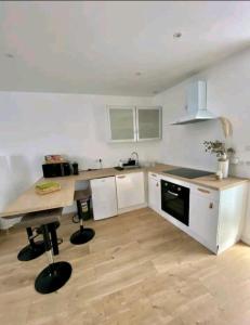 a kitchen with white cabinets and a wooden floor at Maison de ville in Bouguenais