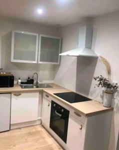 a kitchen with white cabinets and a stove top oven at Maison de ville in Bouguenais