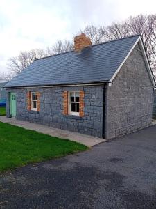 a stone building with two windows and a roof at Fenniscourt Cottage in Carlow