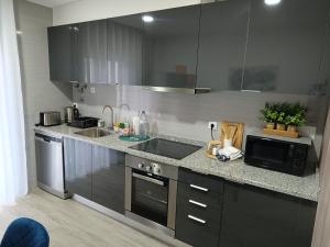 cocina con armarios negros, fregadero y microondas en Garden House Fundão - Suíte 103 com varanda en Fundão
