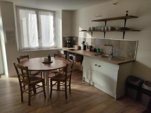 uma cozinha com uma mesa e cadeiras e um lavatório em Les meublés de Louis-Marie, 2 appartements, 8 à 10 personnes, proche du Puy du Fou em Saint-Amand-sur-Sèvre