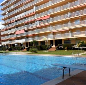 une piscine en face d'un grand bâtiment dans l'établissement Apartamento con gran piscina y frente a la playa., à Malgrat de Mar