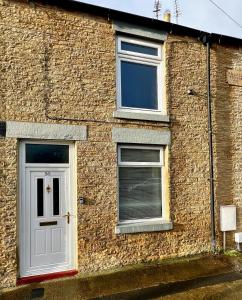 un edificio in mattoni con una porta bianca e due finestre di 50 Etherley Lane a Bishop Auckland