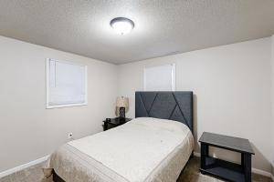 a bedroom with a bed and a table and two windows at Garden Cottage in Rapid City