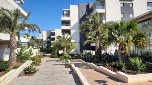 a walkway with palm trees in front of a building at Green Hills La Zenia-Luxury 3 bed Apartment in Los Dolses