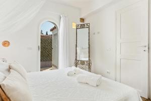biała sypialnia z łóżkiem i lustrem w obiekcie "Villa Adele" w mieście Olbia