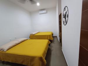 Duas camas num quarto branco com lençóis amarelos em Ideal para compartir momentos especiales 