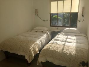 2 camas en una habitación con ventana en Hostal CKAIR, en Bahía Inglesa