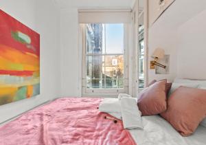 um quarto com uma cama rosa e uma janela em Classic Knightsbridge Loft Apartment em Londres