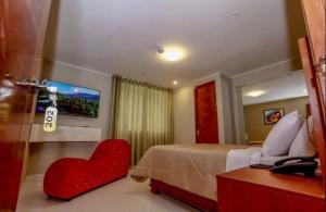 Hotel Cisneros 700 في ليما: غرفة نوم مع سرير وكرسي ذو قلب احمر