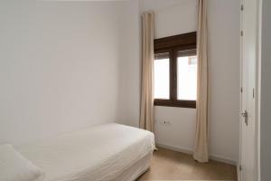 biała sypialnia z łóżkiem i oknem w obiekcie Apartamento Centro Deluxe w Kadyksie