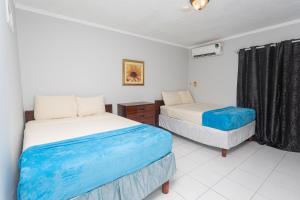 1 dormitorio con 2 camas con sábanas azules y blancas en Caribic House, en Montego Bay