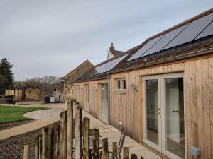 una casa con paneles solares en el techo en The Cow Byre - Cotswold retreat with hot tub, en Dursley