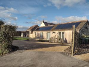 a white house with solar panels on it at The Cow Byre - Cotswold retreat with hot tub in Dursley