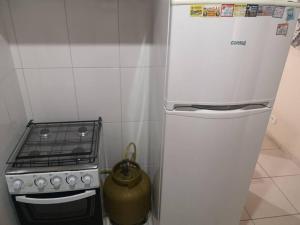 uma pequena cozinha com um fogão e um frigorífico em Apartamento próximo a praia em Marataizes