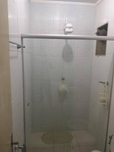 y baño con ducha y puerta de cristal. en Apartamento próximo a praia, en Marataízes