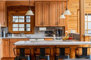 a kitchen with wooden cabinets and a island with chairs at Lake, Kayaks & Sauna - Family & Wellness in Otis
