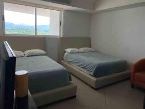 Un dormitorio con dos camas y una ventana. en Relax and Enjoy, en Ixtapa