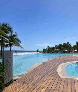 una piscina junto a una playa con palmeras en Relax and Enjoy, en Ixtapa