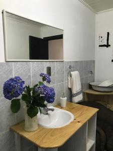 un baño con lavabo con flores púrpuras en un jarrón en Hostel Cala 816, en Frutillar