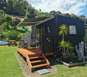 une petite maison noire avec un banc et une table dans l'établissement Pacific Bay HQ - Tutukākā Holiday Unit, à Tutukaka