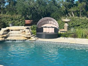 a swimming pool with a fountain next to a swimming pool at Messina Inn in Wimberley