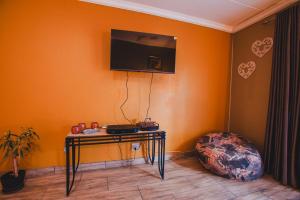 a room with a table and a tv on the wall at I Stay @ De 22 On Vintage in Windhoek