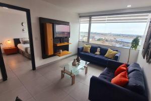 uma sala de estar com um sofá azul e uma televisão em Ecusuites Apartamento Ejecutivo Hotel Sheraton Aeropuerto Quo em Guayaquil