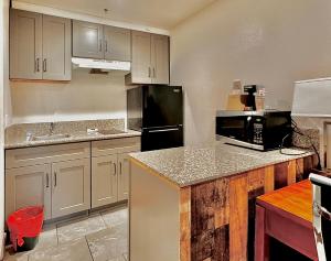 cocina con armarios blancos y nevera negra en City Creek Inn & Suites, en Salt Lake City