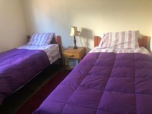 2 łóżka w pokoju z fioletową kołdrą w obiekcie Los Quillayes w mieście Melipilla