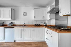 a white kitchen with white cabinets and a sink at Beautiful 5 Bed House Free WIFI in Coventry