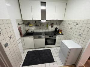 cocina con armarios blancos, fregadero y fogones en Modernes Apartment Saarbrücken, en Saarbrücken