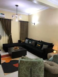 sala de estar con sofá negro y mesa en Furnished 2bedroom Apt in Wuye, en Wupa