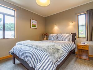 a bedroom with a bed with striped sheets and a window at Ski Country Chalet - Ohakune Holiday Home in Ohakune