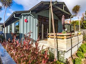 a small green house with a wooden deck at Ski Country Chalet - Ohakune Holiday Home in Ohakune