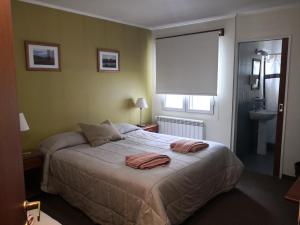 een slaapkamer met een bed met twee handdoeken erop bij Los Lagos Hotel in El Calafate