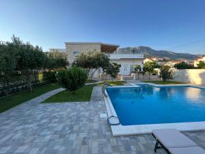 a swimming pool in a yard next to a house at Villa Maci in Kaštela