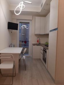 eine Küche mit weißen Schränken sowie einem Tisch und Stühlen in der Unterkunft Cristina in Sanremo