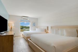 a bedroom with two beds and a flat screen tv at Fisher Inn Resort & Marina in Islamorada