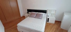 een slaapkamer met een wit bed met 2 kussens erop bij EnBURELA PLAYAS DE ARENA DORADA in Burela de Cabo