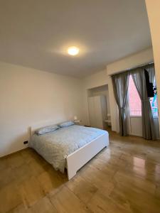ein weißes Schlafzimmer mit einem Bett und zwei Fenstern in der Unterkunft Canelli 3 in Turin