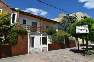 una casa con un cancello bianco e un cartello di Complejo Turístico Hostal Madryn a Puerto Madryn